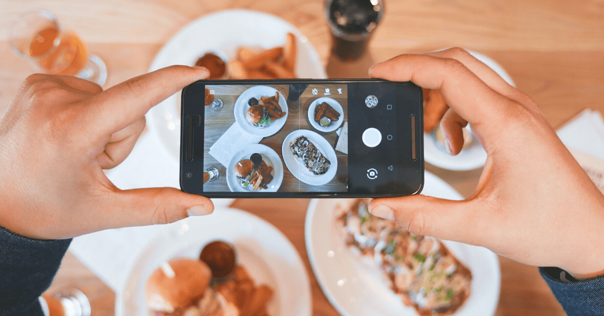 someone taking an overhead photo with an iphone of food on a table